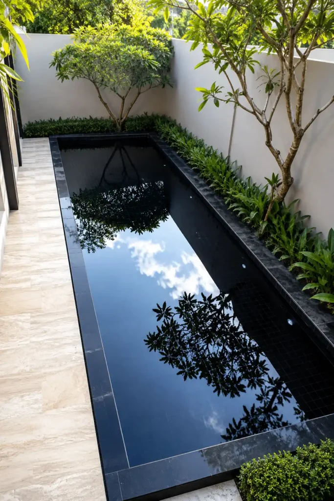 very small garden yard with a compact rectangular plunge pool lined in glossy midnight-black tile.